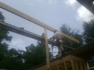 Carpenter setting a ridge beam over a new addition frame — Ice Dam Removal by Roofing Brothers in Proctorsville
