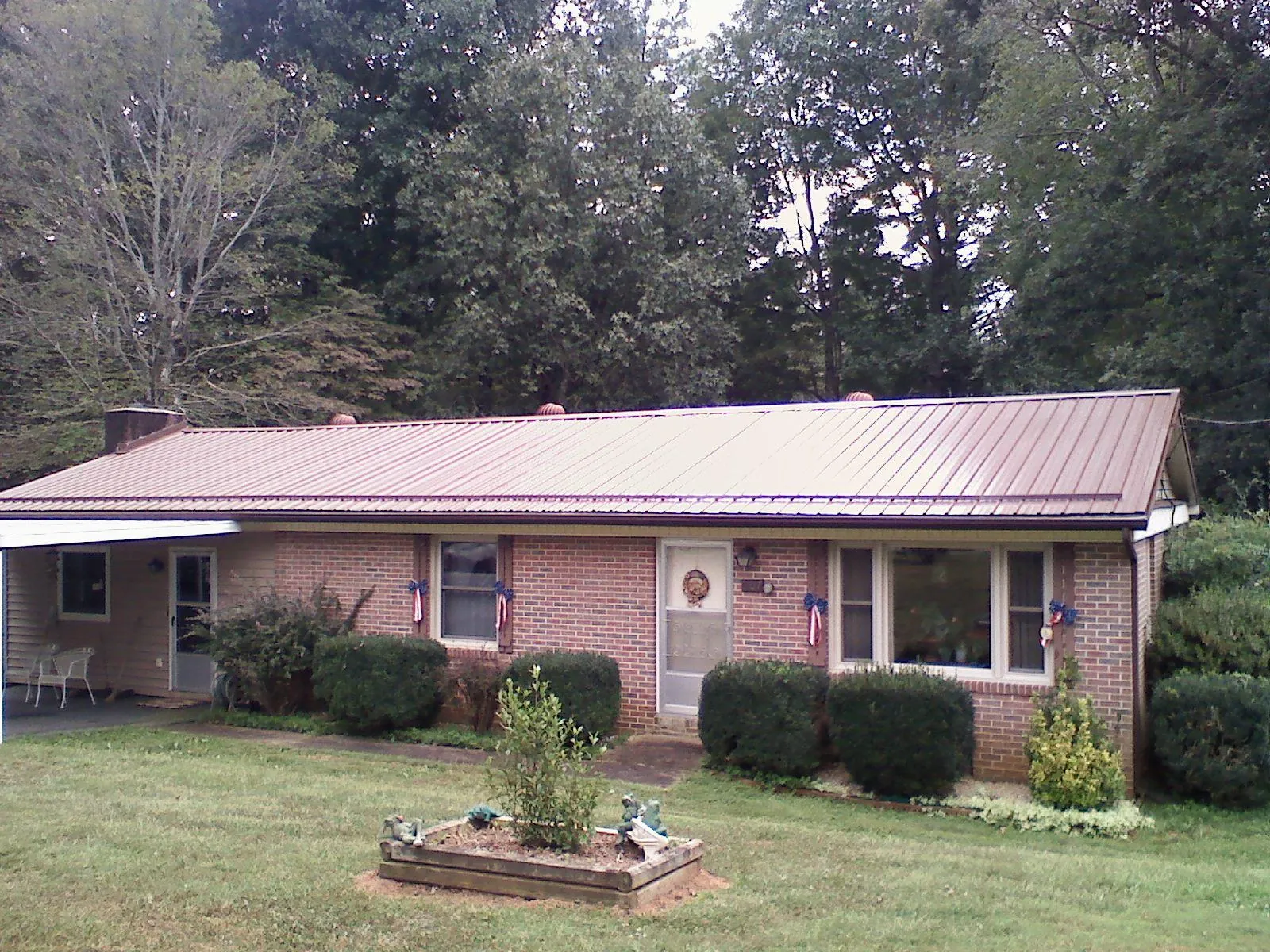Bronze metal roof on a brick ranch home with a carport in Proctorsville