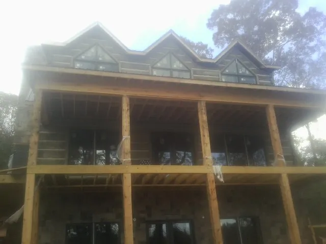 Dormers and porch framing on a large log home under construction — Roof Coating work by our crew in Proctorsville