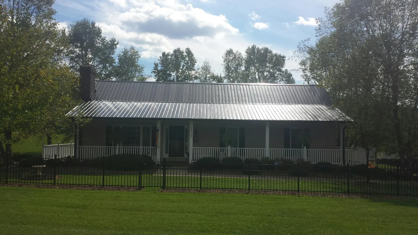 Gray metal roof on a brick ranch with a full width front porch — Gutter Guard Installation work by our crew in Proctorsville