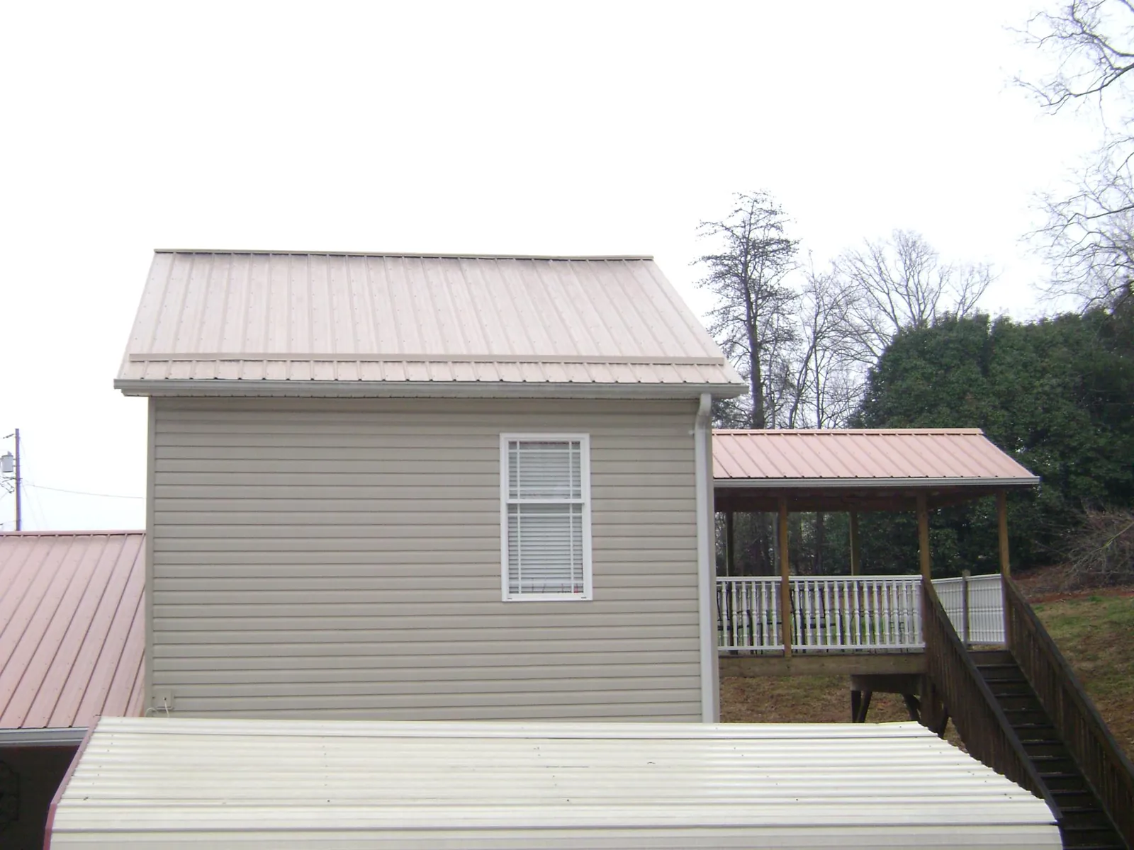 Tan metal roofs on a two story addition and attached porch, from a Roof Replacement job in Proctorsville
