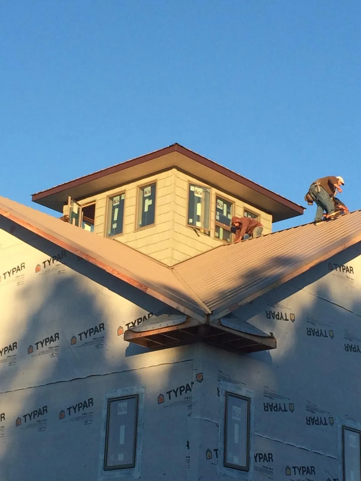 Roofers working around a rooftop cupola on a new metal roof at sunset — Roof Waterproofing in Proctorsville by Roofing Brothers
